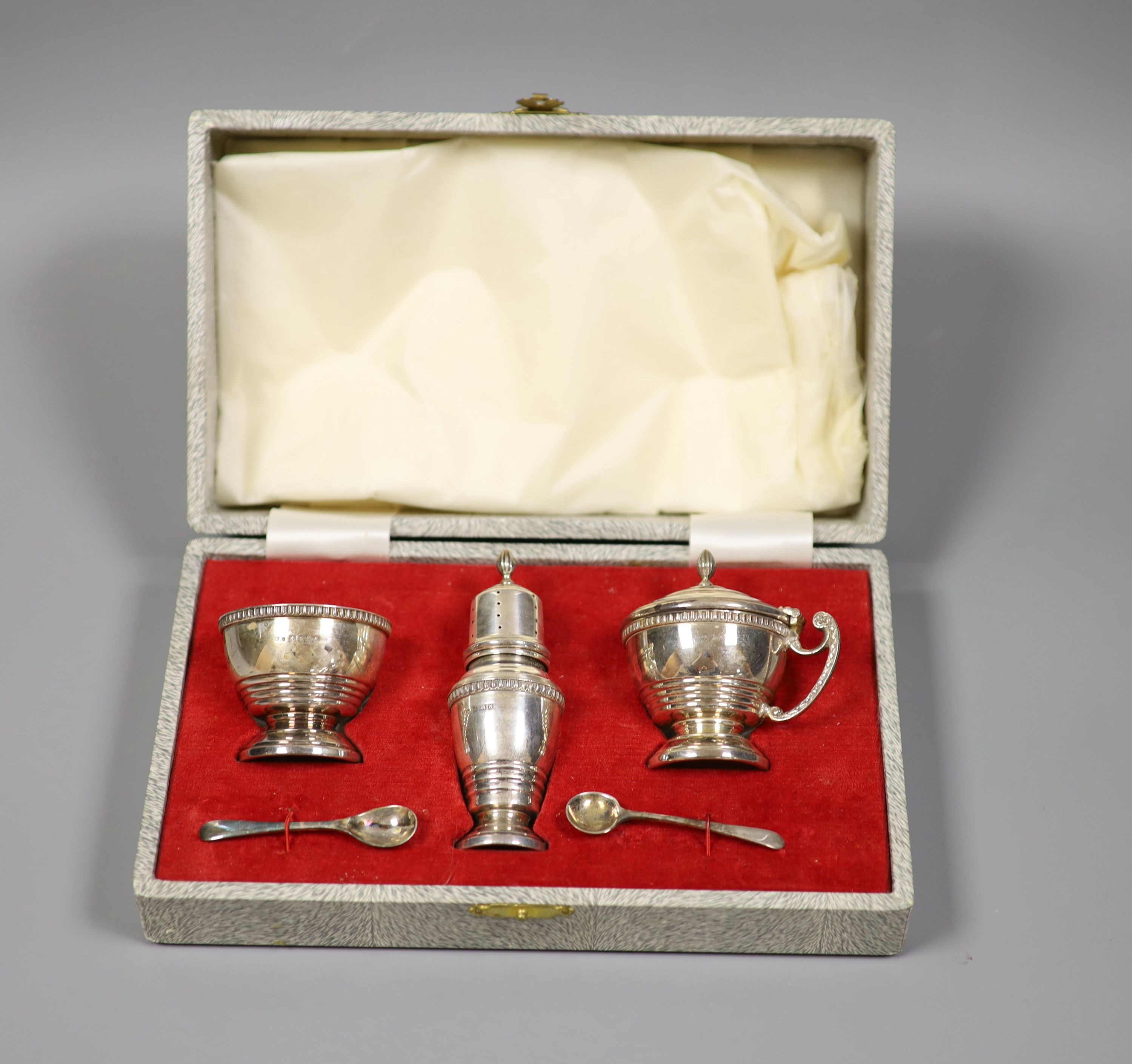 A modern cased silver three piece condiment set, Birmingham, 1955/7, with two associated spoons.